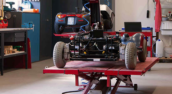 Ein Elektromobil steht auf einer Bühne zwecks Reparatur